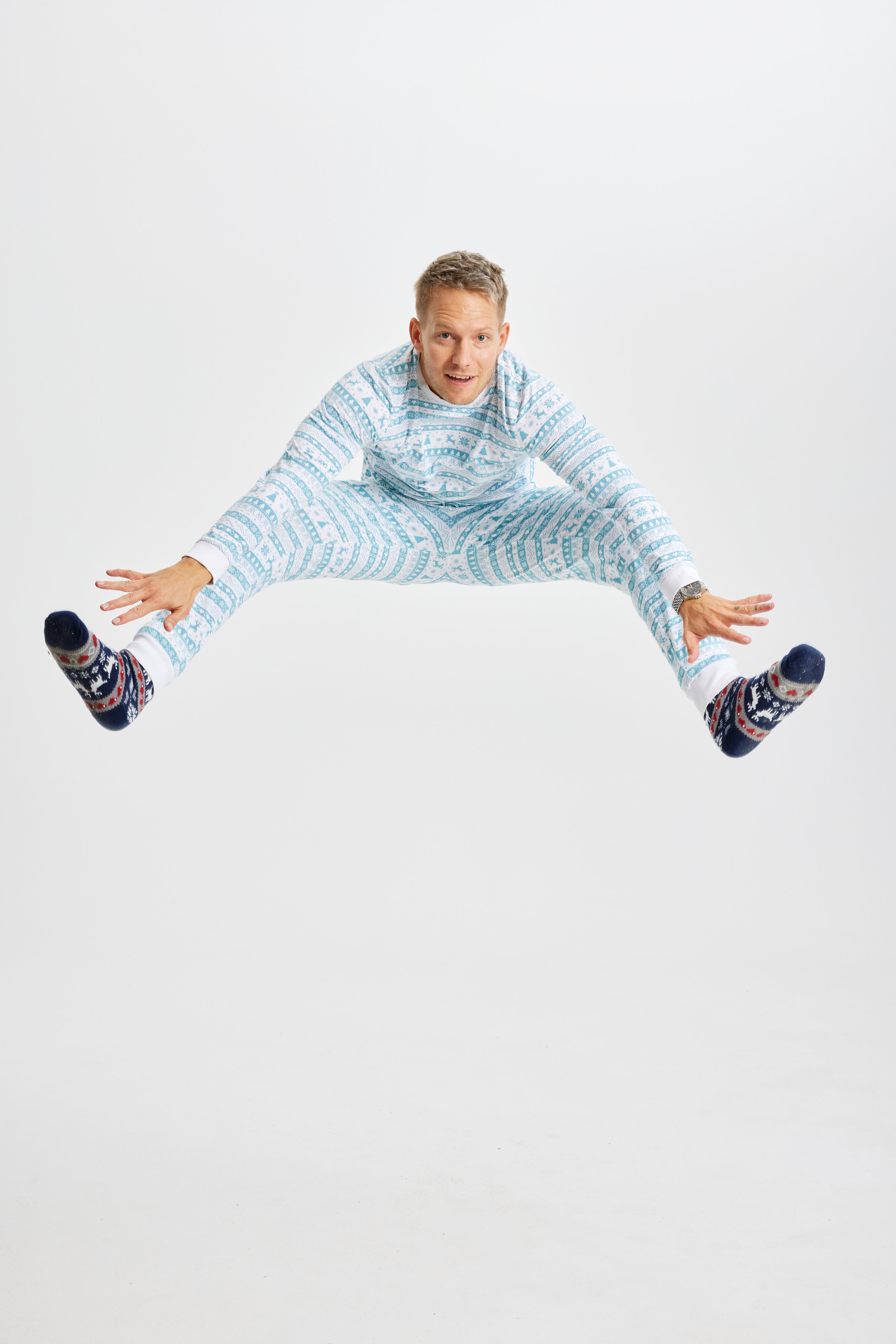 Ein springender Mann in einem hellblauen Weihnachtspyjama.